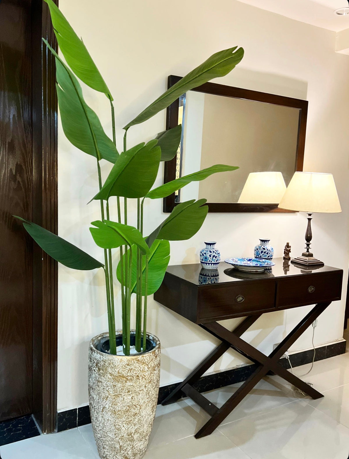 Tall banana palm plant in speckled light gray planter