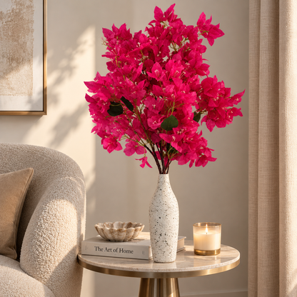 Hot pink bougainvillea stems in a speckled white vase with green leaves