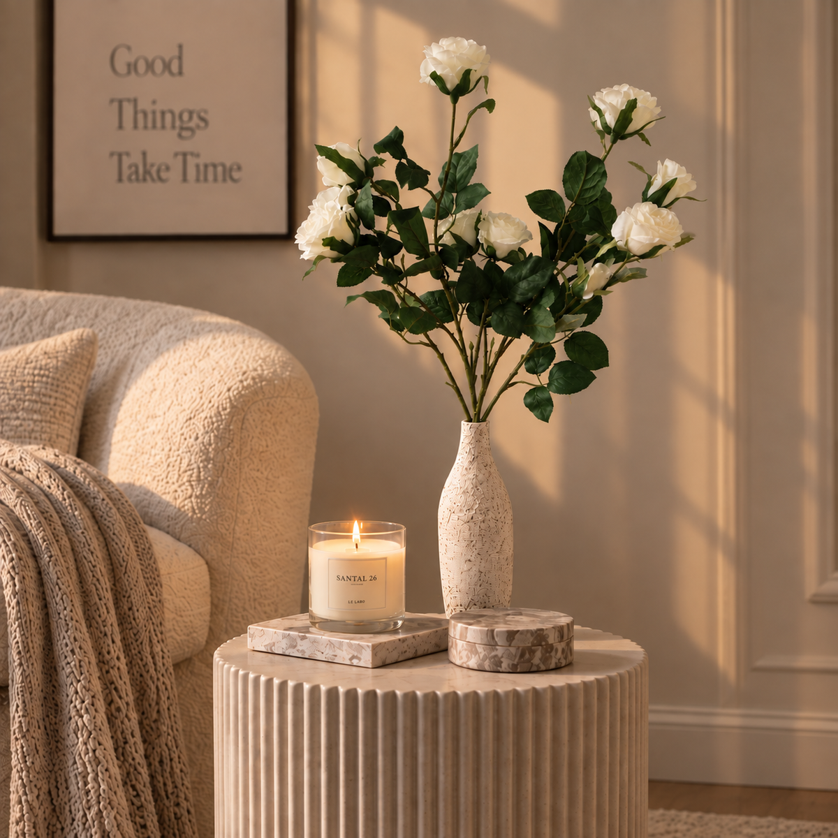 White rose stems with green leaves in speckled beige vase on round table