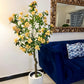 Artificial yellow blossom tree in a white textured pot with green leaves