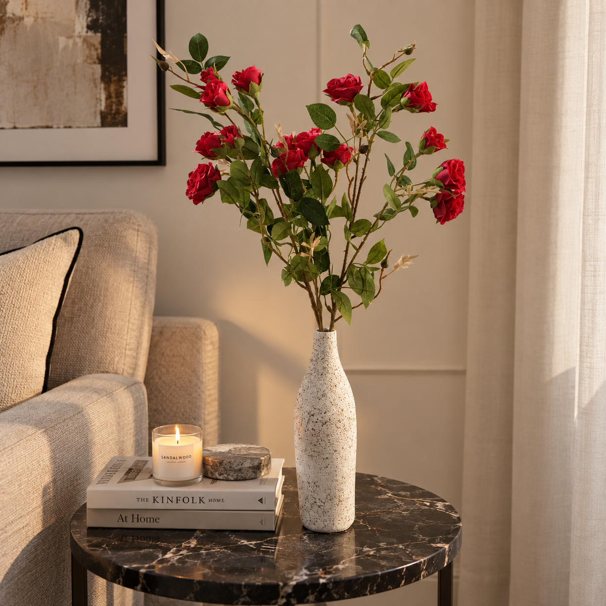Long red rose stems in tall speckled white vase, green leaves and red blooms