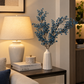 Blue blossom stems in white ceramic vase with long branched stems
