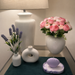 Pink rose bunch in white ceramic vase, with green stems and leaves