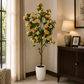 Tall artificial yellow blossom tree with green leaves in a white textured pot
