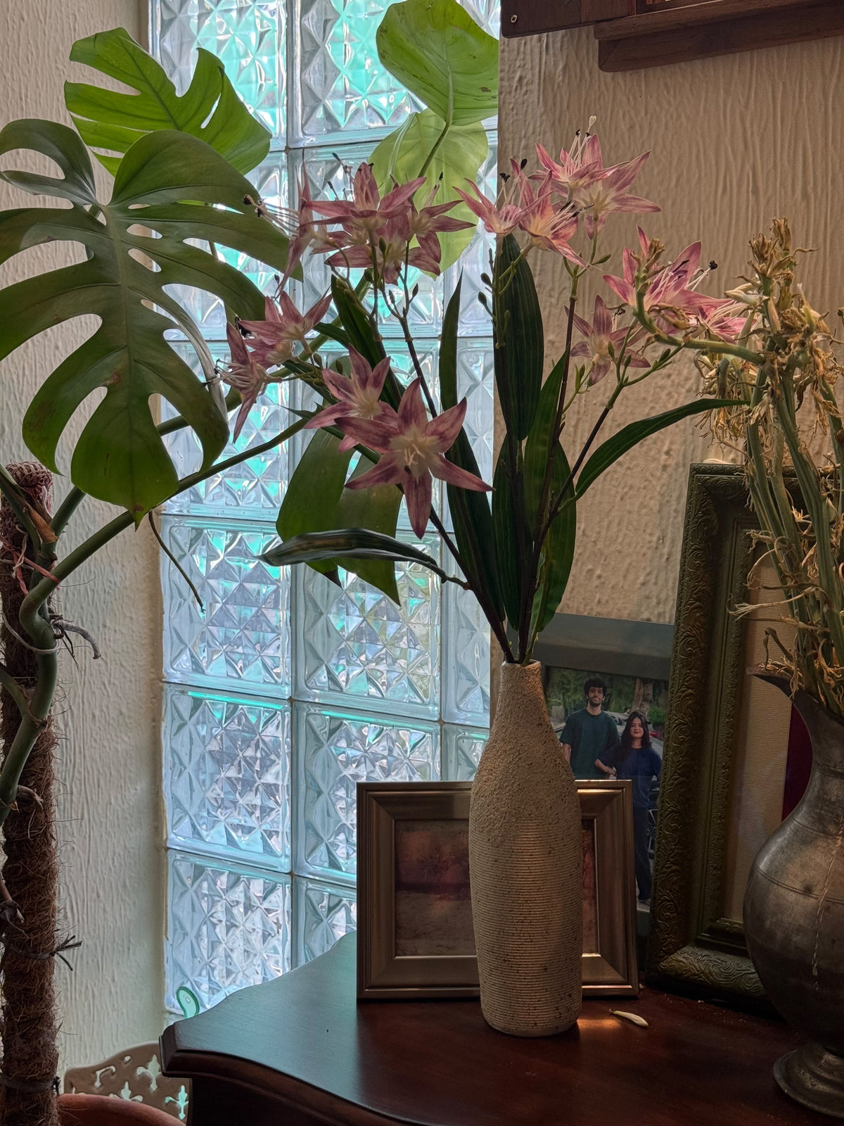 Pink star-shaped flower stems in a speckled ceramic vase with green leaves