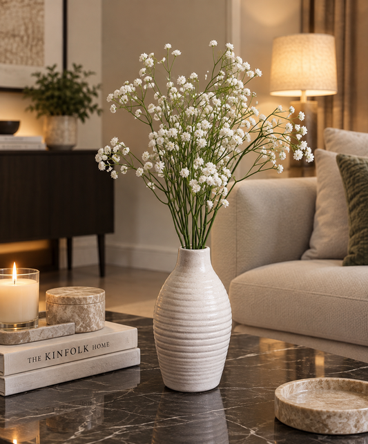 White blossom stems in a ribbed beige ceramic vase on a tabletop